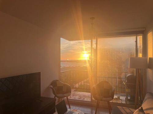 a living room with a view of the sunset through a window at Bordemar, primera línea de playa in El Tabo