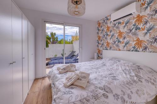 a bedroom with a bed and a large window at Location avec piscine & parking privé à Bandol in Bandol