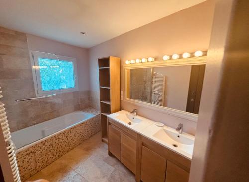 une salle de bain avec deux lavabos, une baignoire et un miroir dans l'établissement La Maison du Soleil, à Saint-Didier