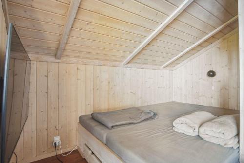 a bed in a wooden room with two towels at Beach House With Sea View Of The Great Belt in Skælskør