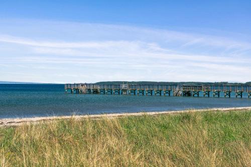 a pier in the water next to a beach at Beach House With Sea View Of The Great Belt in Skælskør