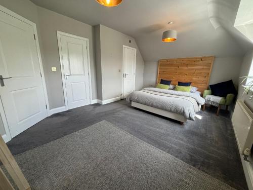a bedroom with a large bed with a wooden headboard at Spacious Apartment NEC BHX in Solihull
