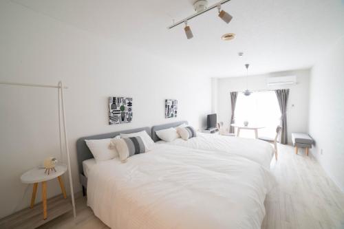 a white bedroom with two beds and a window at Sunny Town-サニータウン- in Osaka