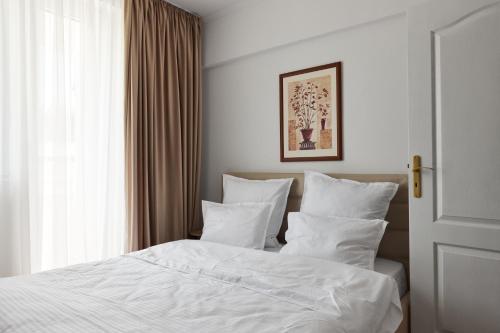 a bedroom with a bed with white sheets and a window at 20 Apartment Centre in Bucharest