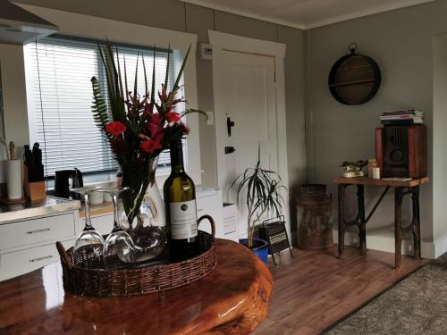 a kitchen with a table with a bottle of wine and flowers at Crown Ridge Miners Cottage in Karangahake