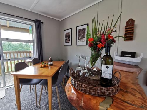 a dining room with a table with a bottle of wine at Crown Ridge Miners Cottage in Karangahake