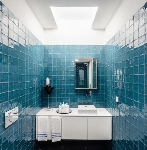 a blue tiled bathroom with a sink and a mirror at Oportolazaro Premium Downtown Porto in Porto