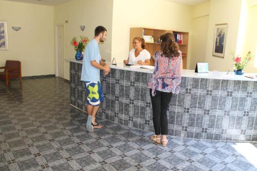 a man and a woman standing at a counter at Amfitriti Hotel & Studios in Lákka