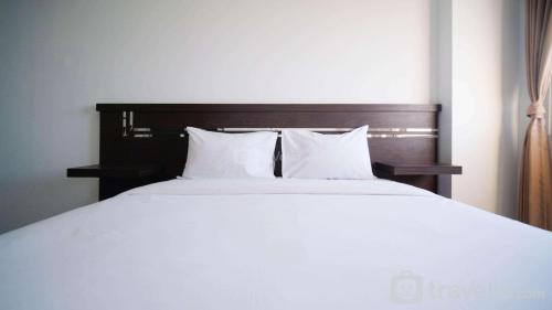 a large bed with white sheets and pillows at Simple 2BR with Extra Bed at Menara Rungkut Apartment By Travelio in Surabaya