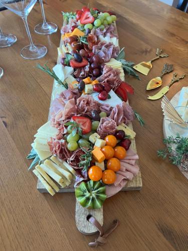 a bunch of different types of food on a wooden table at La Casa Lakeside Resort - Amazing Panoramic View Lakeside House with Pools, Hot Tubs & More! in Kelowna