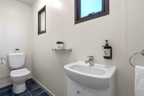 a white bathroom with a toilet and a sink at Tasman Holiday Parks Picton in Picton