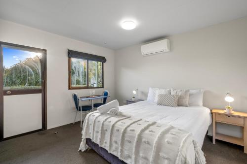 a bedroom with a bed and a desk and a window at Tasman Holiday Parks Picton in Picton