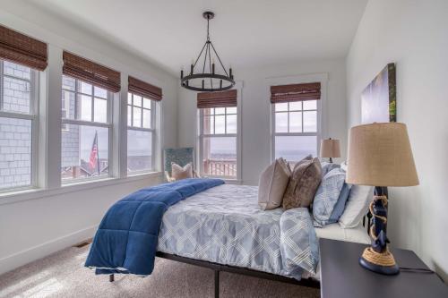a bedroom with a bed with a blue comforter and windows at Searenity Now Depoe Hills in Depoe Bay