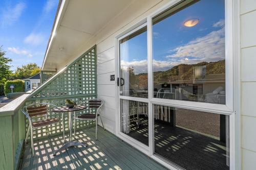 a balcony with a table and chairs and a large window at Tasman Holiday Parks Picton in Picton