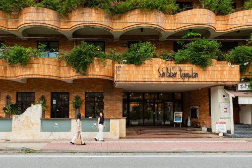 two people walking down the street in front of a building at Sun Palace Kyuyokan in Naha