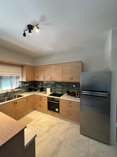 a kitchen with wooden cabinets and a stainless steel refrigerator at Melina house in Ayiá