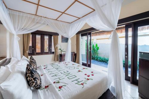 ein Schlafzimmer mit einem weißen Bett mit Blumen darauf in der Unterkunft The Maya Seminyak Villas in Seminyak
