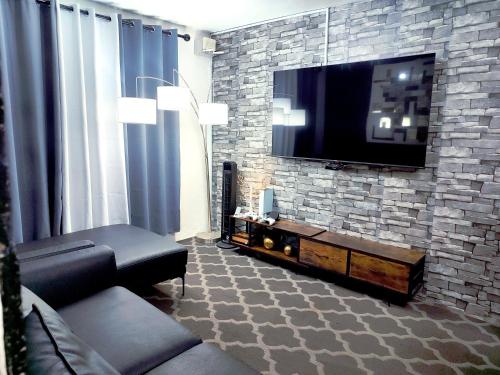 a living room with a flat screen tv on a brick wall at Hogar Pavo Real in Cancún
