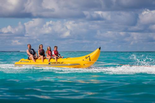 three people riding on a banana boat in the water at Eriyadu Island Resort in Reethi Rah
