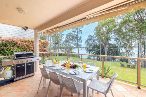 a patio with a table and chairs and a stove at Danalene, 44a Danalene Pde - stunning waterfront property with Air Con, WI-FI, Double Lock Up Garage & Boat Parking in Corlette