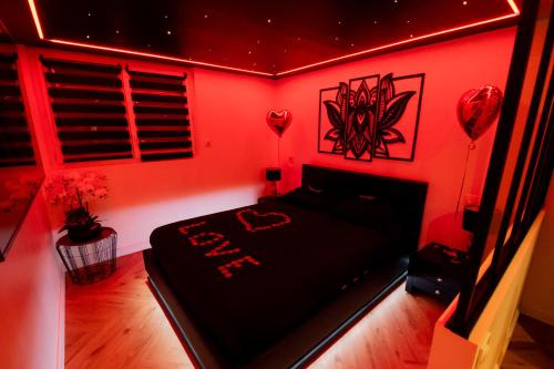 une chambre rouge avec un lit noir avec des lumières rouges dans l'établissement Stella - Appartement détente à Dieppe, à Dieppe
