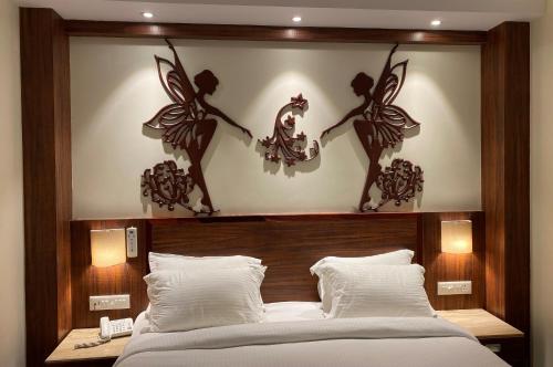 Un dormitorio con una cama con dos querubines en la pared. en Hotel Ami Grace, en Port Blair