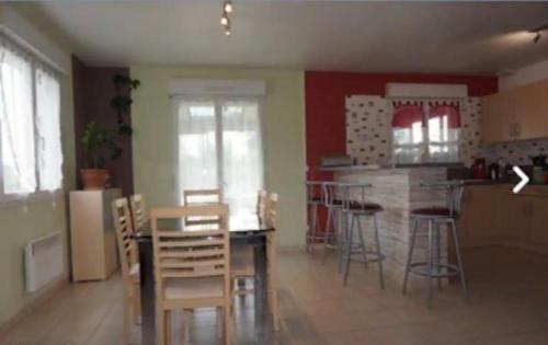 - une cuisine avec une table, des chaises et un bar dans l'établissement Maison de campagne 12 personnes, à Villeloup