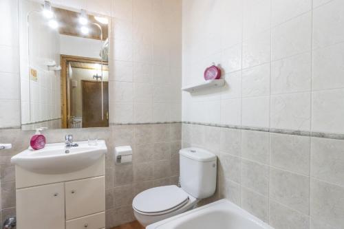 a white bathroom with a toilet and a sink at El Raco De Cal Maró in Vall de Castellbò