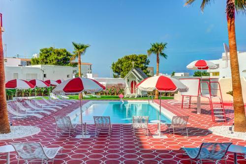 a pool with chairs and umbrellas and palm trees at Romeos Ibiza - Adults Only in San Antonio Bay