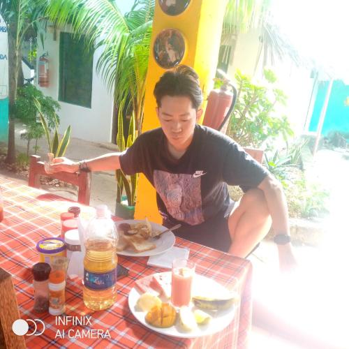 a man sitting at a table with a plate of food at HOMELAND SWAHILI LODGE Nungwi Backpacker Apartments BUDGET in Nungwi