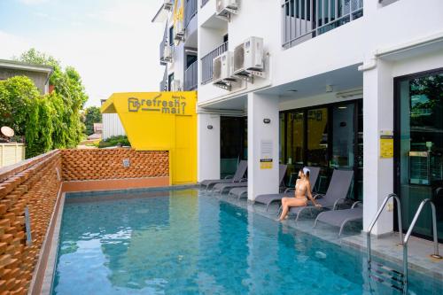 a woman sitting on the edge of a swimming pool at a hotel at Sleep Mai Thapae Chiang Mai Old City Lifestyle Hotel in Chiang Mai