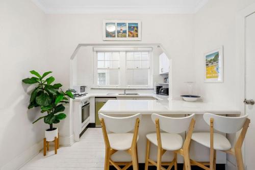a white kitchen with a table and four chairs at Manly Harbour in Sydney