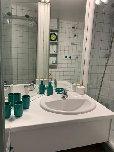 une salle de bain avec un lavabo avec des tasses vertes dessus dans l'établissement Appartement Saint-Cyprien Plage avec piscine, à Saint-Cyprien