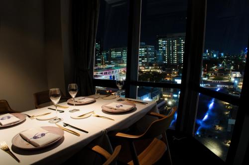 a dining table with a view of a city at night at The Tower Hotel Nagoya in Nagoya
