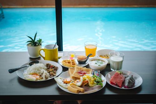 a table topped with plates of breakfast foods and drinks at Sleep Mai Chiang Mai Airport Lifestyle Hotel in Chiang Mai