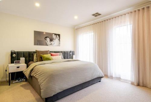 Un dormitorio con una cama grande y una ventana. en Luxury Family Holiday Rental On the Mornington Peninsula, en Frankston South
