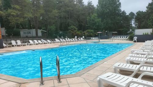 une grande piscine avec des chaises longues blanches et des chaises dans l'établissement Mobil home Côte d'Opale, à Camiers