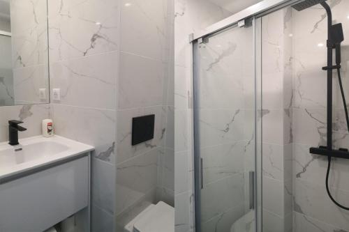 une salle de bain blanche avec une douche et un lavabo dans l'établissement Cosy Studio Héliopolis H Village Nat Vue mer, au Cap d'Agde