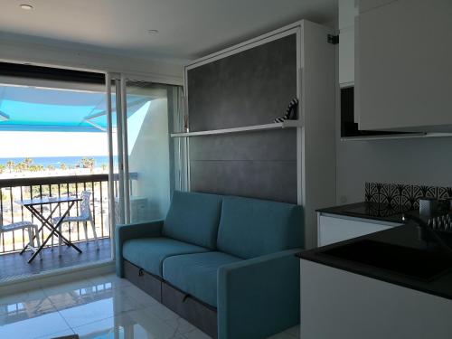 un salon avec un canapé bleu et un balcon dans l'établissement Cosy Studio Héliopolis H Village Nat Vue mer, au Cap d'Agde