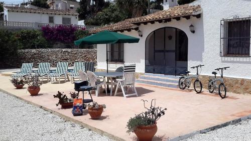 a patio with chairs and a table with an umbrella at Villa Casa Nuestra in Moraira
