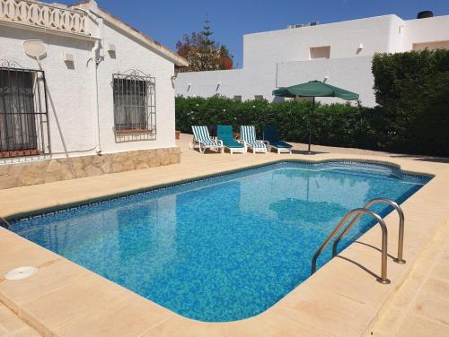 a swimming pool with chairs and an umbrella at Villa Casa Nuestra in Moraira