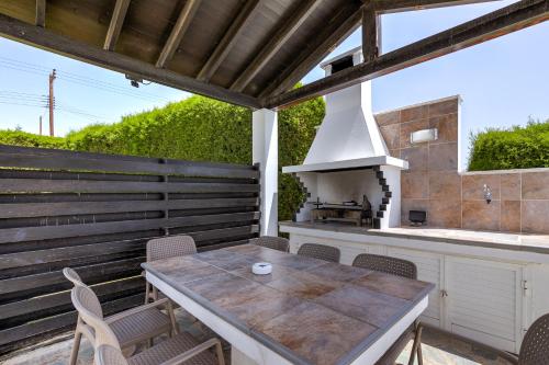 an outdoor kitchen with a wooden table and a stove at Platzia Beach Villas in Paphos City