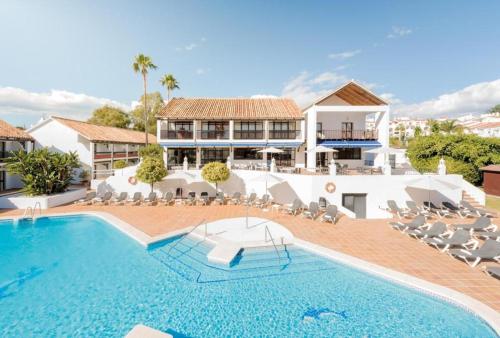 a swimming pool with chairs and a house at Ona Diana Park in Estepona