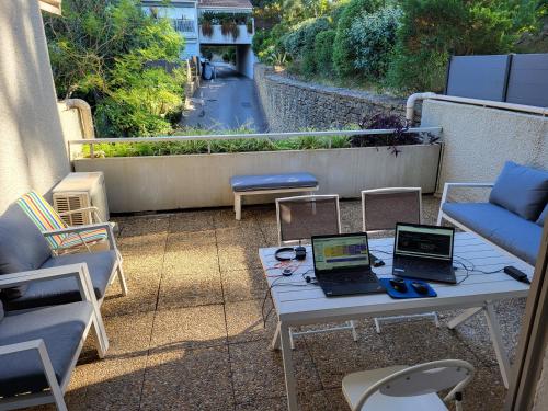 2 ordinateurs portables assis sur une table sur une terrasse dans l'établissement Apartement bord de mer parking terasse, à La Ciotat