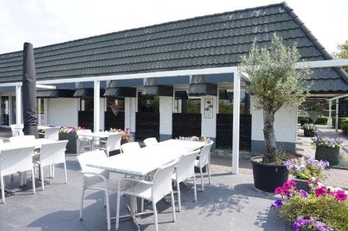 a restaurant with white tables and white chairs and flowers at Kustverhuur, Park Schoneveld, Zeester 63 in Breskens