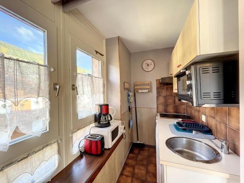 une petite cuisine avec un évier et un micro-ondes dans l'établissement Ceylan - appartement - 5 pers - centre, aux Gets