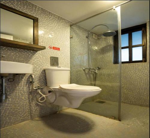 a bathroom with a toilet and a glass shower at Ronne's Casa De Piscina Privada 3BHK VILLA in Verla