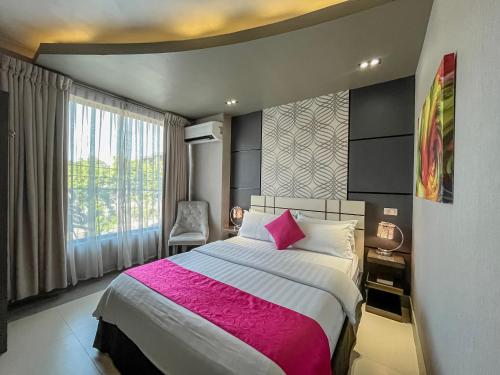 a bedroom with a large bed with a pink blanket at Eloisa Royal Suites in Mactan
