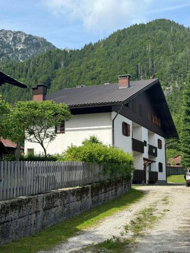 a white house with a black roof and a fence at Casa Margherita - Valbruna in Valbruna