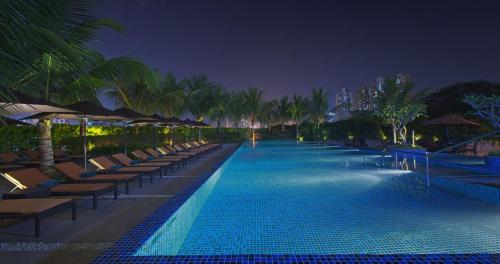 a swimming pool with chairs and umbrellas at night at The Westin Mumbai Garden City in Mumbai